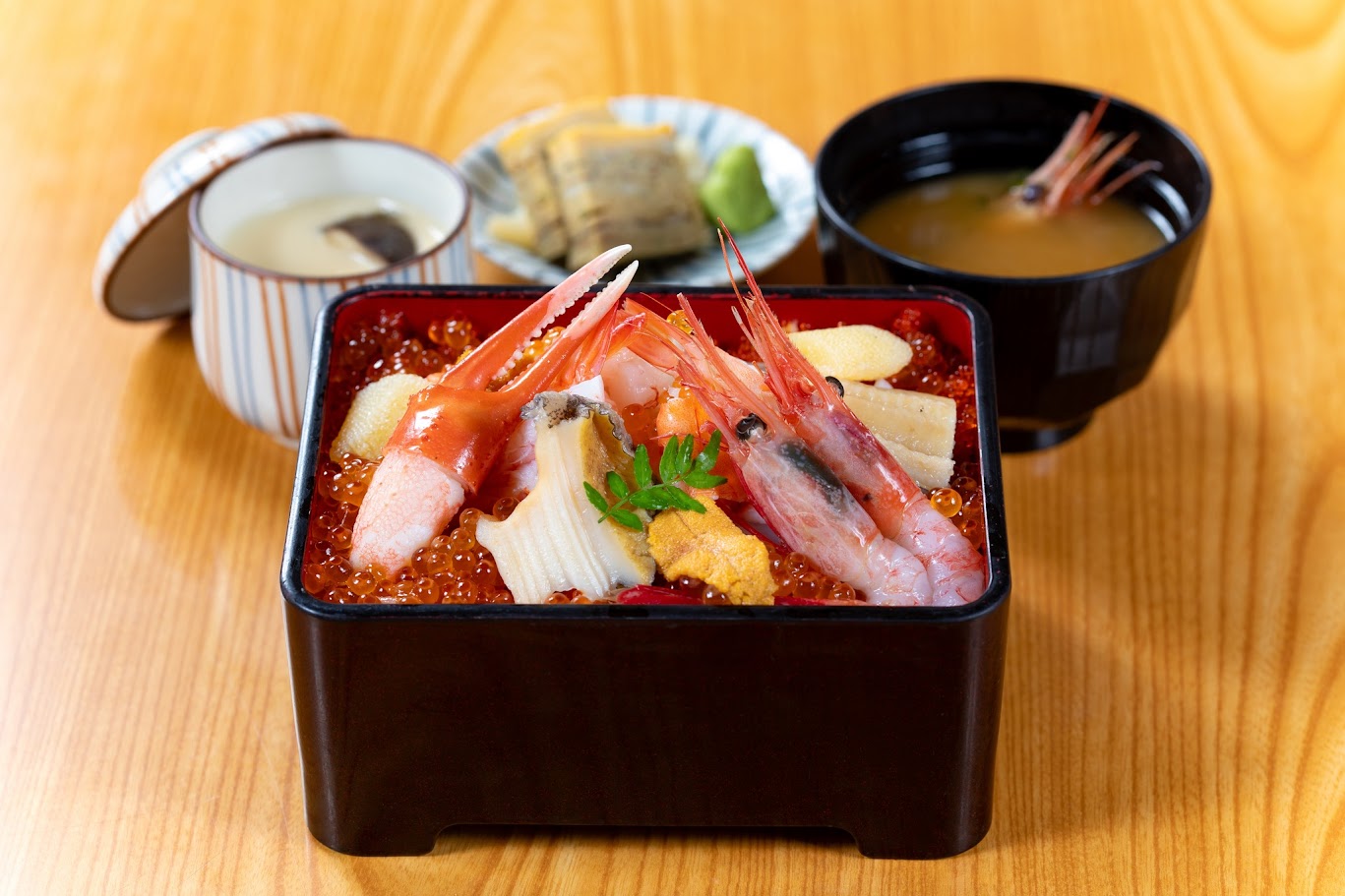 ข้าวหน้าทะเลญี่ปุ่นรวมกุ้ง ปู ไข่ปลาแซลมอน และอูนิ จัดเสิร์ฟในกล่องสี่เหลี่ยม พร้อมซุปมิโสะและเครื่องเคียง เหมาะสำหรับสายกินที่วางแผน เที่ยวญี่ปุ่น