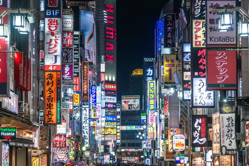 ย่าน Shinjuku โตเกียวตอนกลางคืน เต็มไปด้วยแสงไฟนีออนและป้ายร้านค้าหลากสีสัน หนึ่งใน ที่เที่ยว shinjuku โตเกียว ที่คึกคักและมีชีวิตชีวาที่สุดในญี่ปุ่น