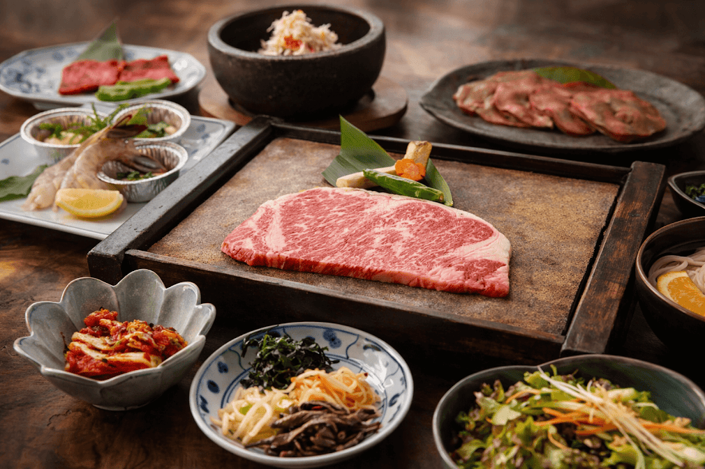 รวมสุดยอดร้านปิ้งย่างระดับตำนานญี่ปุ่น สเต๊กเนื้อวากิวลายหินอ่อนย่างบนเตาหิน เสิร์ฟพร้อมเครื่องเคียงสไตล์ญี่ปุ่นและชุดผักสด บรรยากาศโต๊ะไม้แบบดั้งเดิมสุดพรีเมียม