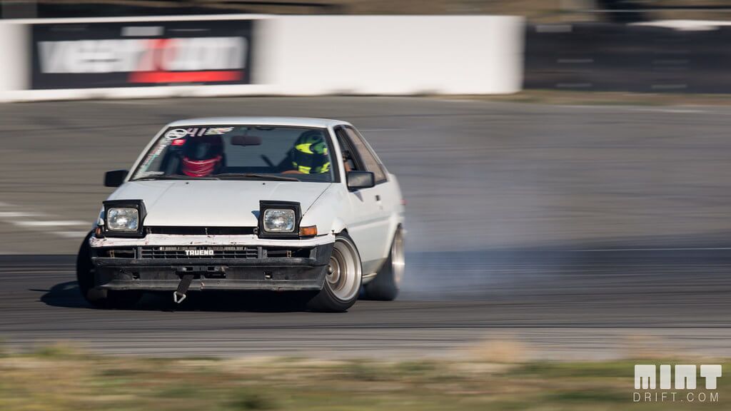 รถdriftญี่ปุ่น Toyota AE86 Trueno กำลังดริฟต์ในสนามแข่ง มีควันยางด้านหลัง แสดงถึงรถดริฟต์ระดับตำนานของวงการมอเตอร์สปอร์ตญี่ปุ่น 🚗💨🇯🇵