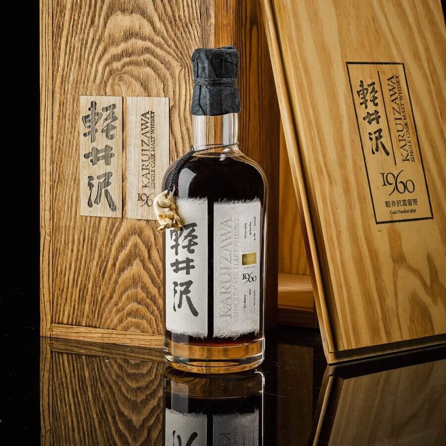 
ขวดวิสกี้ญี่ปุ่น Karuizawa รุ่นหายากวางอยู่บนพื้นผิวสะท้อนเงา คู่กับกล่องไม้ดีไซน์คลาสสิกด้านหลัง แสดงถึงความพรีเมียมและความหายากของแบรนด์ระดับตำนาน สื่อถึงภาพลักษณ์ของ เหล้าญี่ปุ่นที่แพงที่สุด ในวงการนักสะสม