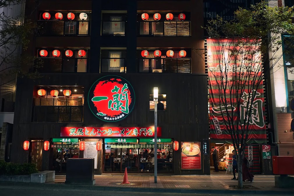 ขับรถเที่ยวฟุกุโอกะ รถเช่าญี่ปุ่น แวะกินราเมนร้านดังย่านกลางคืนใน Fukuoka บรรยากาศร้านสไตล์ญี่ปุ่นโคมแดงสวยงาม นักท่องเที่ยวกำลังนั่งรับประทานอาหารหน้าร้าน