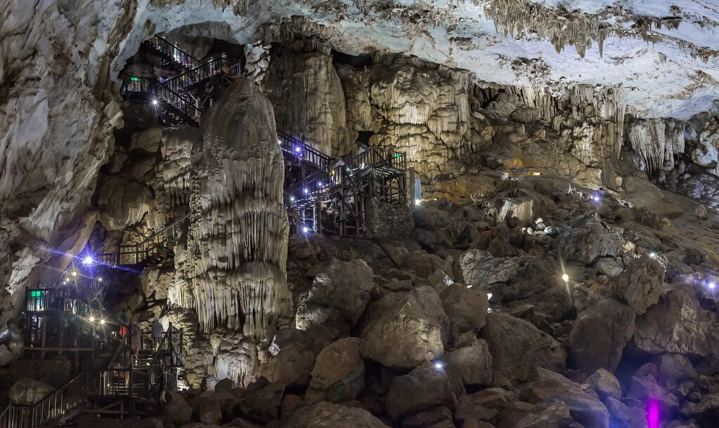 ที่เที่ยวเวียดนาม: ภายในถ้ำหินงอกหินย้อยขนาดใหญ่ มีทางเดินและบันไดไม้พร้อมไฟส่องสว่าง โอบล้อมด้วยโขดหินและโครงสร้างธรรมชาติอันน่าตื่นตาตื่นใจ