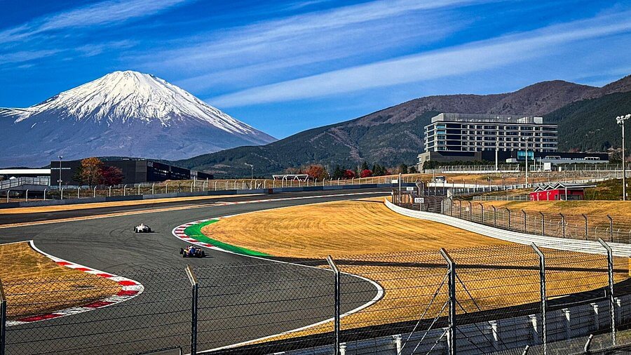 ภาพโค้งความเร็วของ Fuji Speedway โดยมี Mount Fuji เป็นฉากหลัง รถแข่งกำลังเข้าโค้งในสนามระดับโลกของ ญี่ปุ่น เหมาะกับคำค้นหา “สนามแข่งรถญี่ปุ่น มีที่ไหนบ้าง”