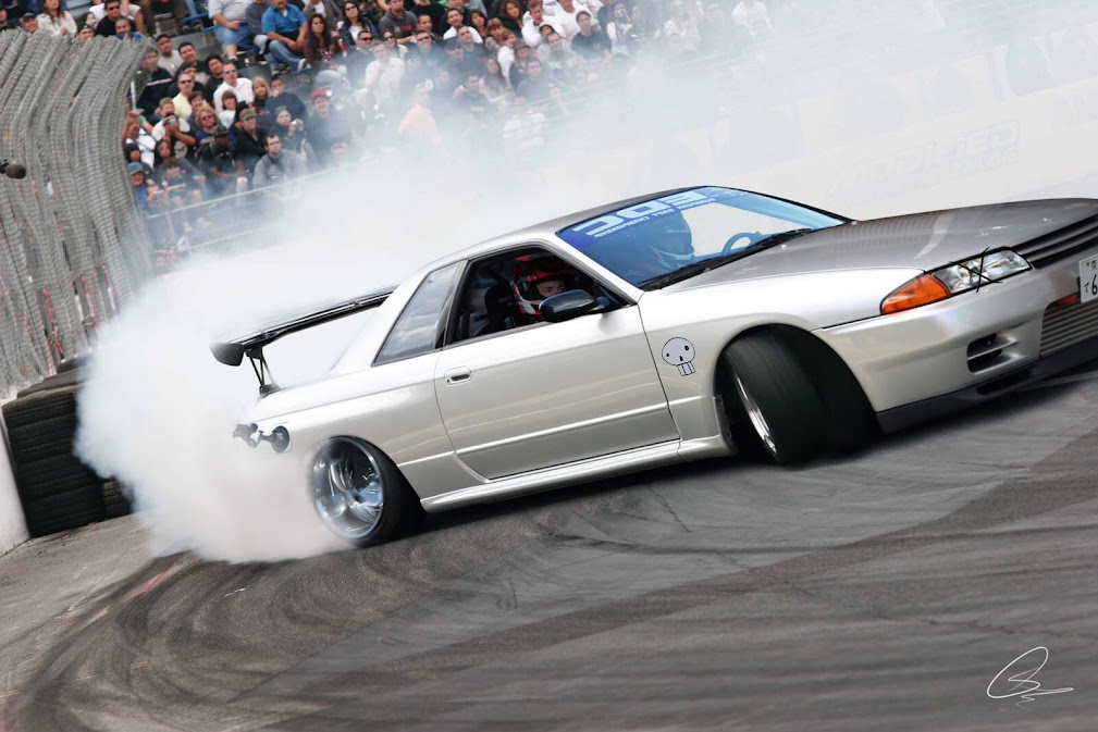 รถdriftญี่ปุ่น Nissan Skyline GT-R กำลังดริฟต์ในสนามแข่ง มีควันจากยางลอยหนาแน่น แสดงถึงรถสปอร์ตระดับตำนานและวัฒนธรรมดริฟต์ของญี่ปุ่น 🚗💨🇯🇵